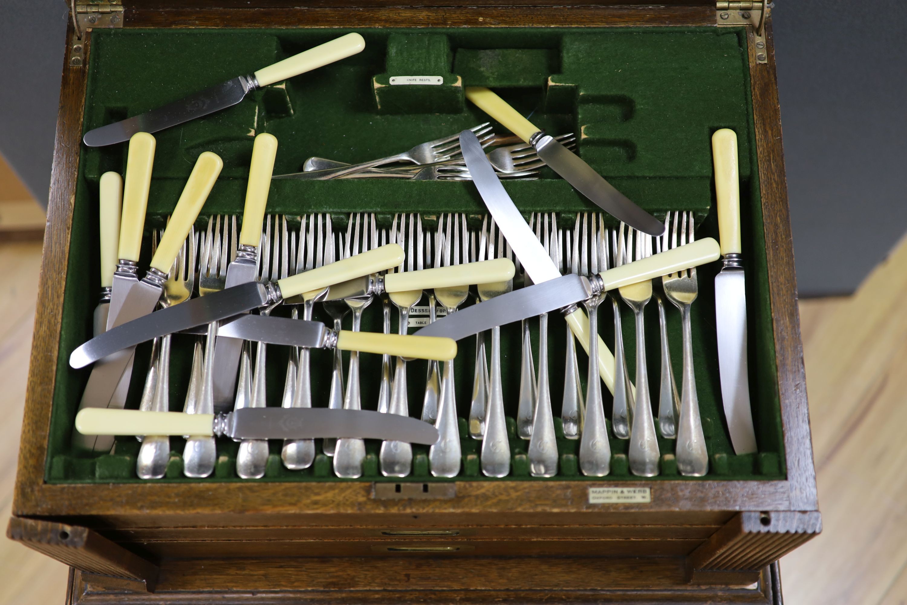 An Edwardian oak cased silver plated table canteen, settings for twelve and a set of silver plated fish knives and forks for twelve